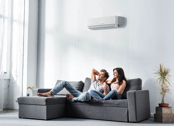 smiling couple on couch air conditioner cool room